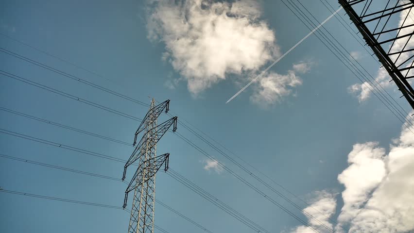 Vienna, Austria - 05.27.2025: The artificial Danube Island, created in the 1970s and 1980s. High-voltage power lines and a passenger plane flying overhead.