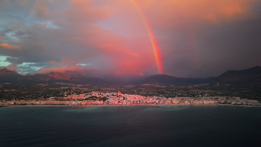Aerial view of the Spanish town of Altea at sunset with a vivid rainbow above the mountains and colorful clouds over the Mediterranean coast