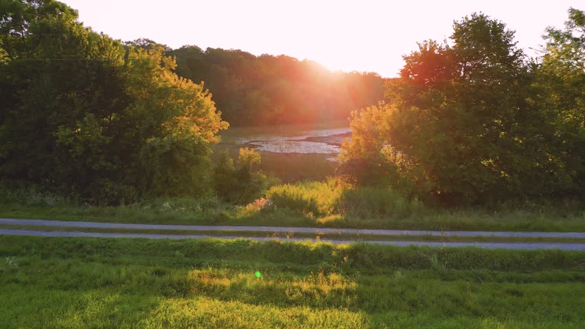 Sunset over a grassy field and pond summer relaxation vibes | Drone Flyover a country meadow leading to a marsh with bugs and texture