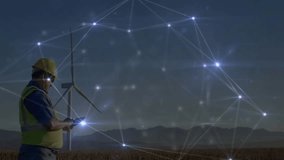 Male technician using tablet in wind farm at dusk, showcasing energy technology network graphics. Renewable, energy, industry, digital, technology, outdoors, infrastructure - Powered by Shutterstock - Get 15% off with code: PIKWIZARD15