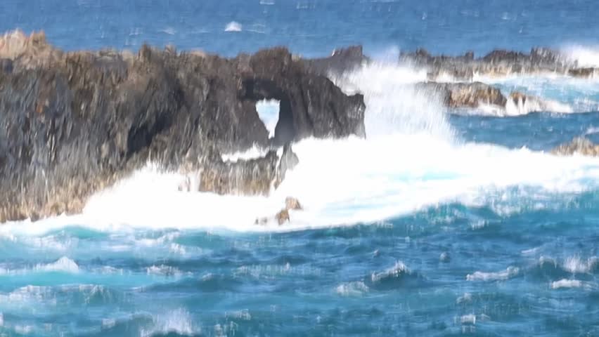 Slow motion video shows powerful ocean waves crashing against rugged volcanic rocks on the coastline near Kapalua, Maui, Hawaii, with mist rising and turquoise water swirling dramatically.