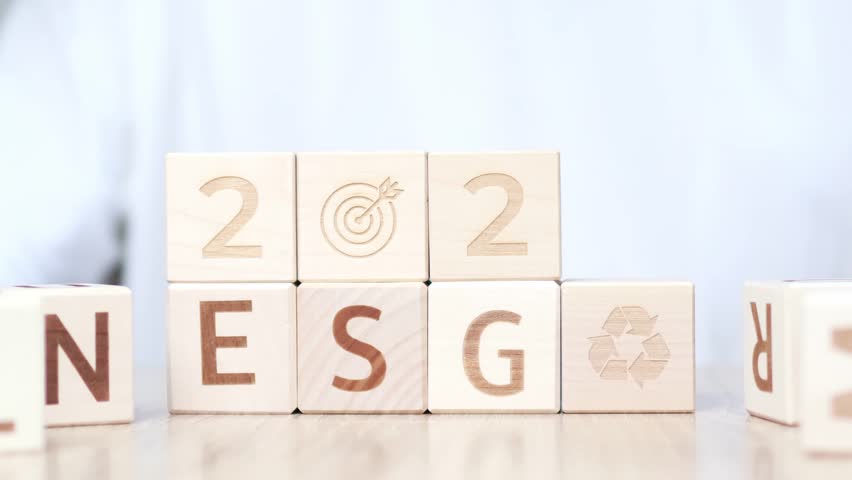 A person arranges wooden blocks displaying goals for 2026. The blocks feature various symbols and letters, illustrating a method for organizing and visualizing aspirations