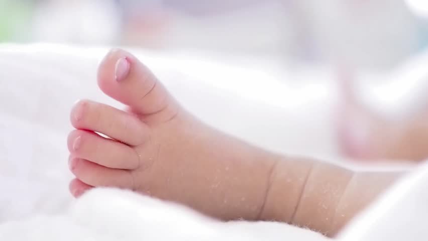 Close up of newborn baby feet on white blanket