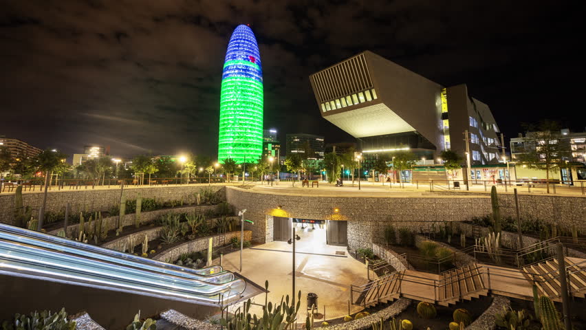 Timelapse of Glories Metro Station In Barcelona and skyline and torre agbar lit up at night