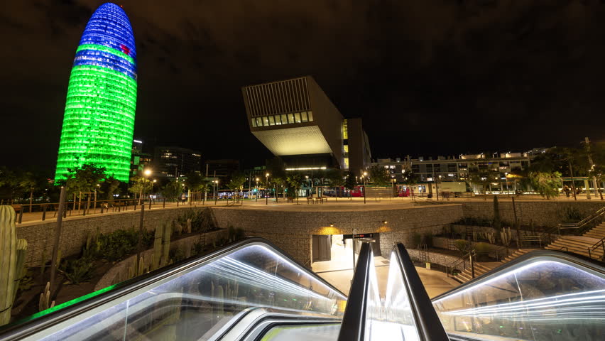 Timelapse of Glories Metro Station In Barcelona and skyline and torre agbar lit up at night