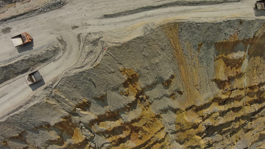 Aerial top view of open pit copper ore mine and heavy mining equipment. Excavator and mining trucks in quarry, 4k