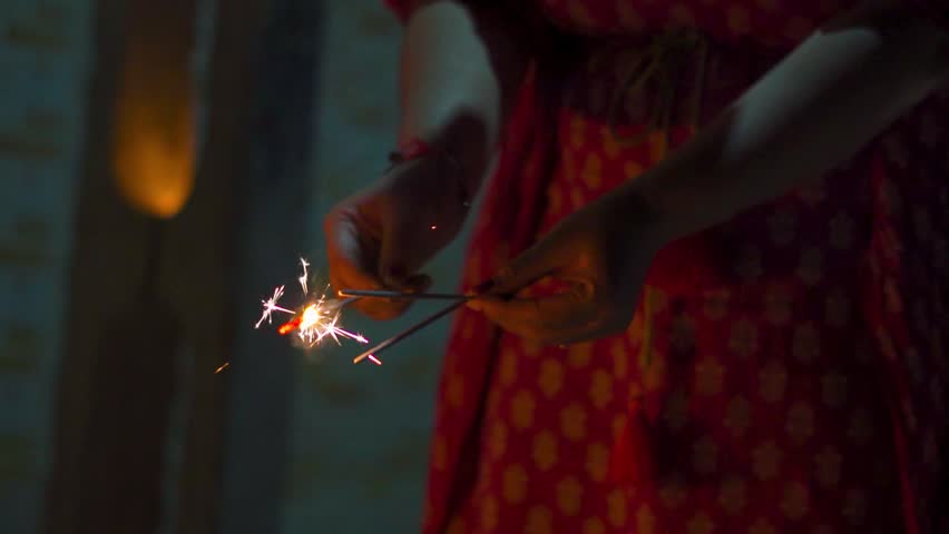 Indian female bursting pencil crackers (phuljhadi) during Diwali night in Gujarat, India. Diwali Festive and vibrant atmosphere. New year and people celebrating festivals.
