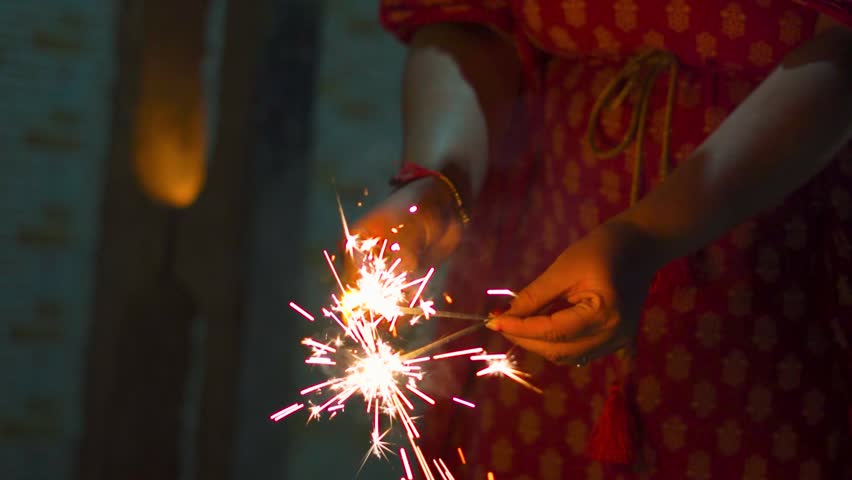 Indian female bursting pencil crackers (phuljhadi) during Diwali night in Gujarat, India. Diwali Festive and vibrant atmosphere. New year and people celebrating festivals.
