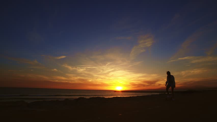 Silhouette of a woman skateboarding at sunset