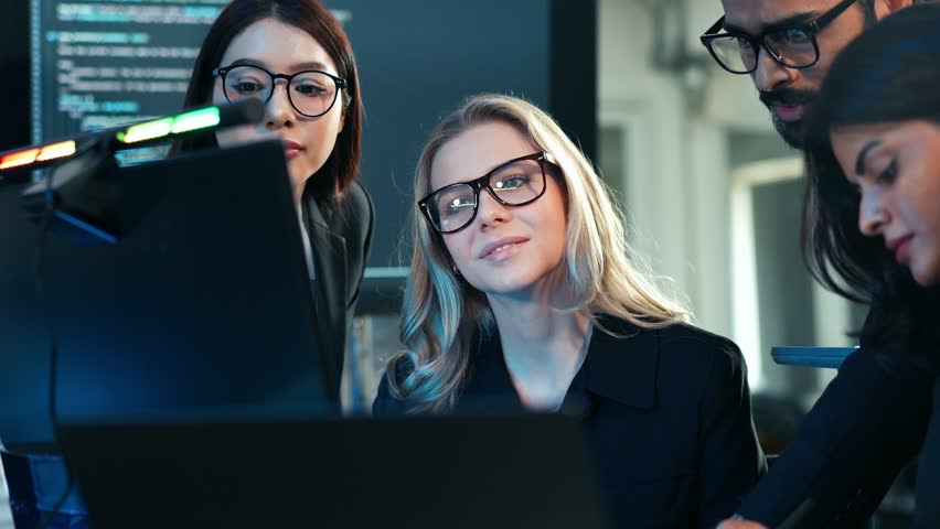 Diverse team of business professionals and developers collaborating on a digital project, focusing on code and data analysis in a dark, tech-savvy office. Cybersecurity and IT work. - Powered by Shutterstock - Get 15% off with code: PIKWIZARD15