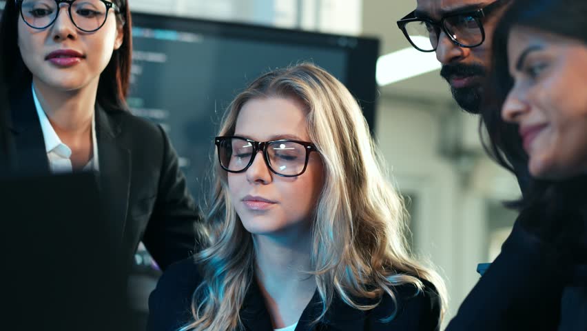 Diverse team of business professionals and developers collaborating on a digital project, focusing on code and data analysis in a dark, tech-savvy office. Cybersecurity and IT work. - Powered by Shutterstock - Get 15% off with code: PIKWIZARD15