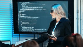Female IT professional leads a business meeting. Presenting software code and data on screen to team. Women's leadership, technology training, and successful project management in a corporate business - Powered by Shutterstock - Get 15% off with code: PIKWIZARD15