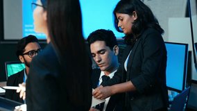 Multicultural business and IT professionals collaborating and checking data on a computer in a secure, dark corporate office. Concepts of intense teamwork, cybersecurity, and digital work. - Powered by Shutterstock - Get 15% off with code: PIKWIZARD15