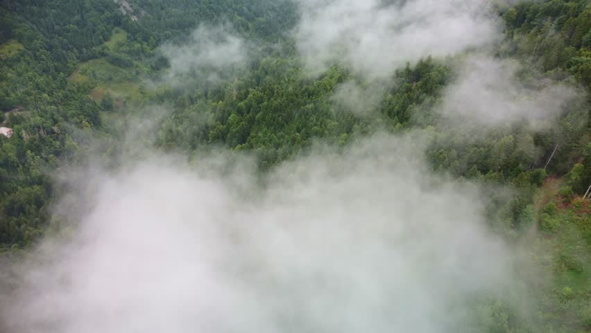 Aerial footage flies over clouds lying low over a mountain forest area of southern France.