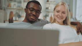Happy interracial loving couple using laptop at home, choosing apartment or trip. Portrait of african american man embracing his beautiful blonde girlfriend when viewing pictures at computer screen - Powered by Shutterstock - Get 15% off with code: PIKWIZARD15