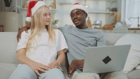 Happy multiethnic couple celebrating Christmas vacation, portrait at home. Beautiful blonde woman and african american man sitting on sofa, cheating and using laptop, happy interracial marriage - Powered by Shutterstock - Get 15% off with code: PIKWIZARD15