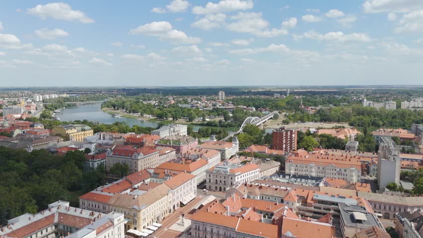 Aerial capturing the Ferenc Móra Museum, Belvárosi Bridge, and the Tisza River, revealing Szeged’s harmony of architecture and water.