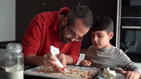 Dad and son decorating holiday cookies with frosting - Powered by Shutterstock - Get 15% off with code: PIKWIZARD15