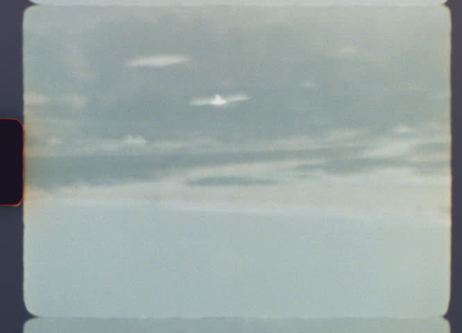 Vintage super 8 film footage showing unidentified flying object hovering above a distant coastline with atmospheric grain and soft focus