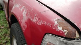 Severe rust corrosion and peeling paint damage on red car hood edge above headlight showing metal deterioration - Powered by Shutterstock - Get 15% off with code: PIKWIZARD15