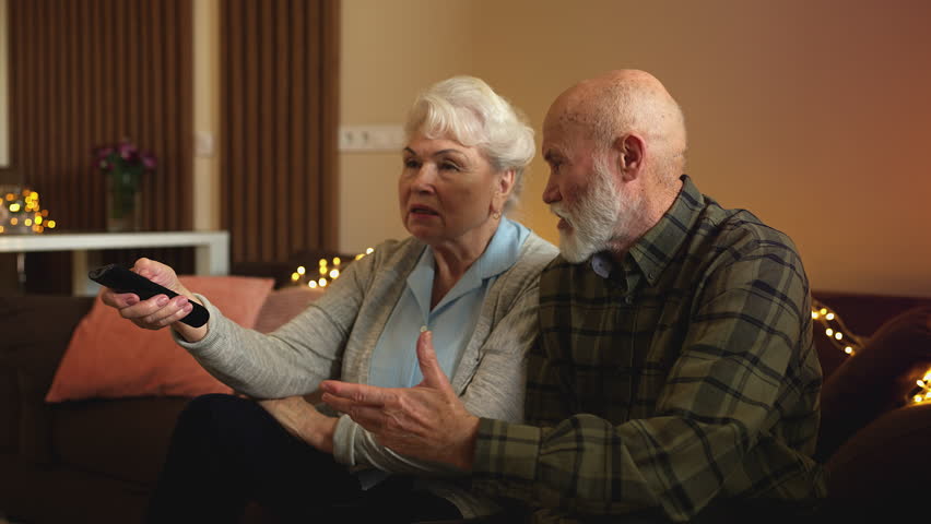 Elderly man bickering about politics with wife while watching evening news on TV