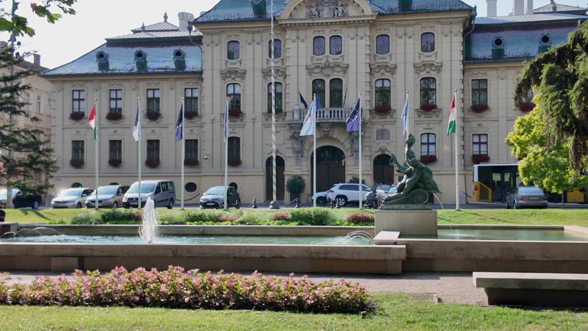 Pan shot moving from a fountain in front of Szeged City Hall to the historic town hall tower, highlighting architectural details.