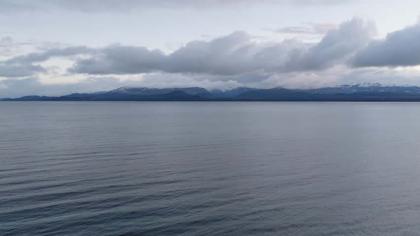 Nahuel Huapi lake water reflecting a cloudy sky, with mountains in the distance, showing the expanse and calm atmosphere of the scenic Patagonian region in Argentina