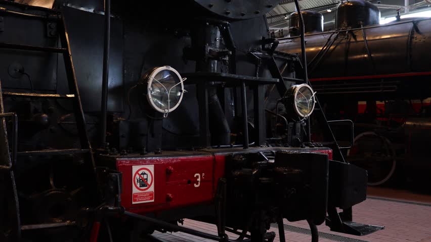 Old steam train engine on display with bright red accents and black body, great for nostalgia or industrial settings.