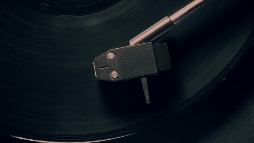 Retro Vinyl record player playing music, close-up macro shot of vintage LP disc old phonograph spinning. Retro music player at home.