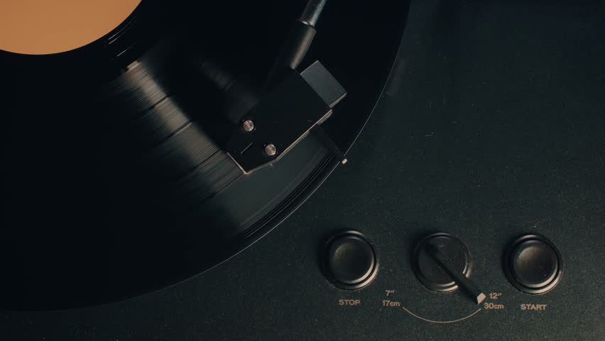 Retro Vinyl record player playing music, close-up macro shot of vintage LP disc old phonograph spinning. Retro music player at home.