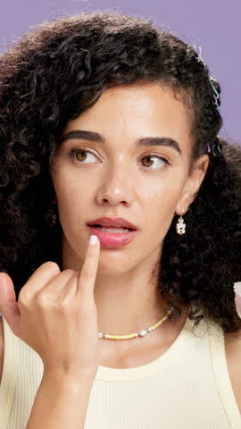 Woman, face and finger for lip balm in studio for moisturizer, beauty or makeup on purple background. Girl, person and product with container, gloss and confidence with cosmetics in Costa Rica