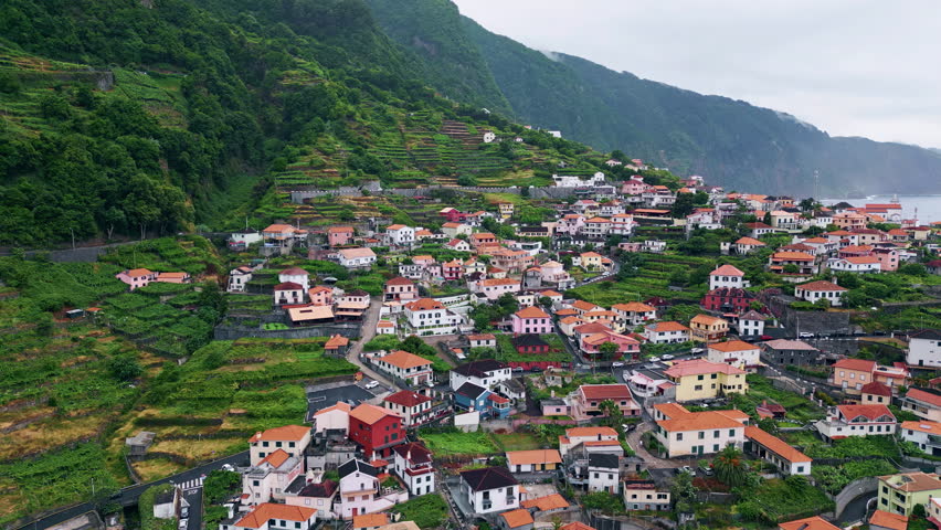 Forest countryside at cloudy day nature aerial. Panoramic picturesque mountain architecture landscape under thunder clouds. Cozy houses placed on green woodland hills. Fresh valley village slow motion