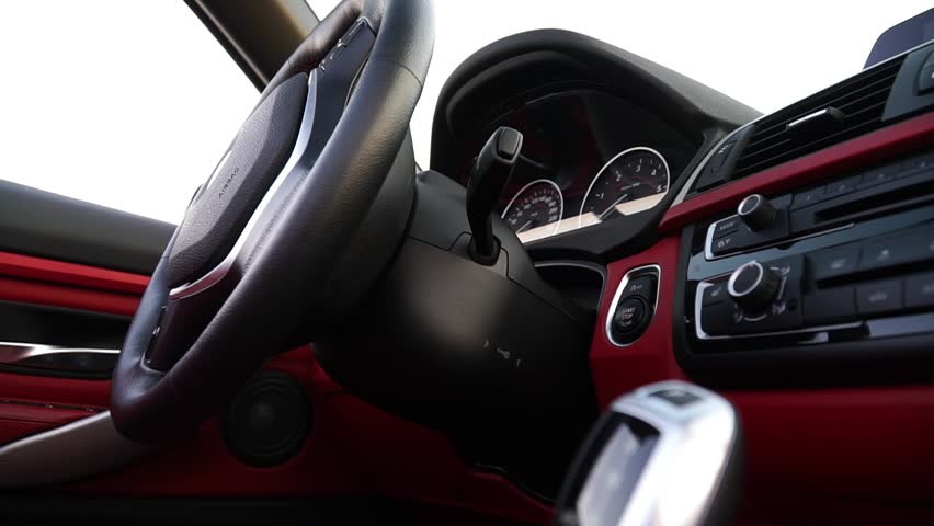 Close-up view of car interior showcasing steering wheel, dashboard, and gear shift, capturing the dynamic essence of driving experience with vibrant red accents and sleek design elements