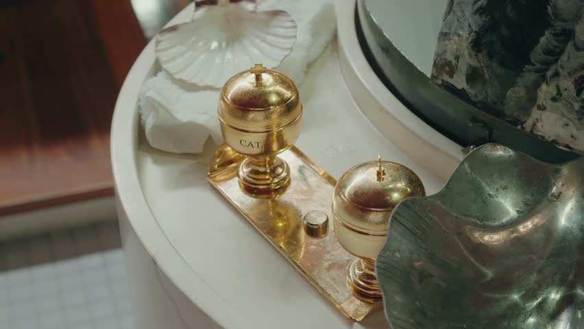 golden chrism containers and seashell placed on a baptismal font used for ceremonial anointing