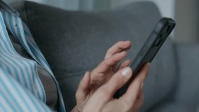 A woman in casual clothes sitting comfortably on a couch at home, using her smartphone and browsing or texting in a relaxed setting. - Powered by Shutterstock - Get 15% off with code: PIKWIZARD15