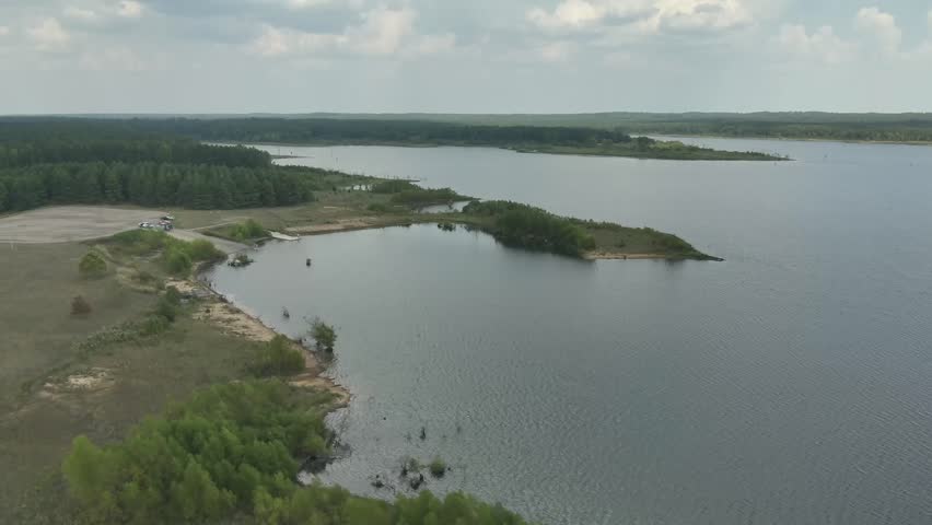 Aerial drone footage of a lake. Short, ten second, clip of a lakeshore with boat ramp and trucks parked in a parking lot, from a 4k drone.