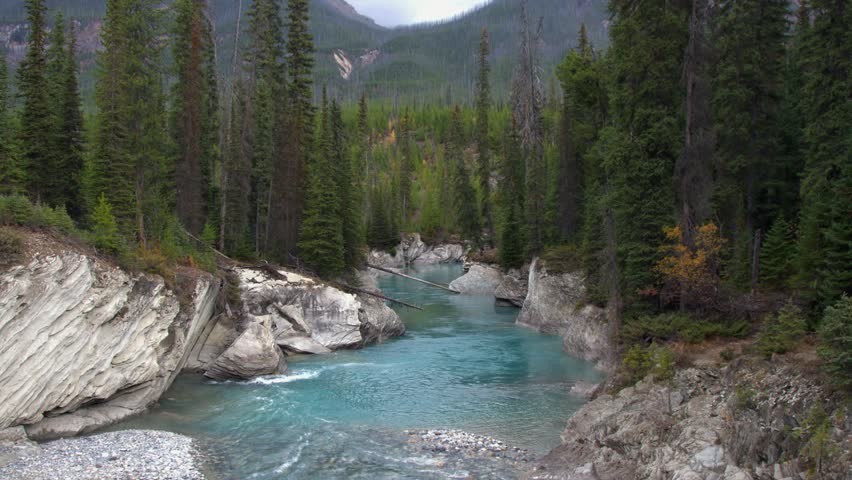 Nature scene: Glacial blue river runs through rocky canyon in mountains