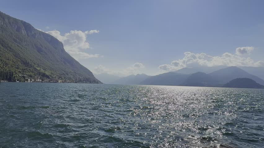 Panoramic Horizontal View of Lake Como with Gentle Ripples and Green Mountains in a sunny day
