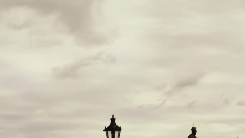 Charles Bridge Prague slow motion cinematic 4K B roll footage with Gothic tower, Baroque statues, autumn colors, and historic architecture in cinematic cityscape views. This faceless B roll delivers serene background footage with ample copy space, captured in a minimalist style under natural lighting for clean composition. The cinematic footage reveals gentle pedestrian movement across the bridge, vibrant autumn foliage framing ornate Baroque statues, and majestic Gothic tower details against the river, evoking a timeless mood and elegant atmosphere in high resolution. Ideal as a commercial background for storytelling visuals in modern lifestyle and travel projects, perfect for advertising, marketing, branding, social media, websites, presentations, corporate videos, and creative productions.