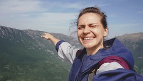 A cheerful young woman takes a selfie against the backdrop of mountains during her trip - Powered by Shutterstock - Get 15% off with code: PIKWIZARD15