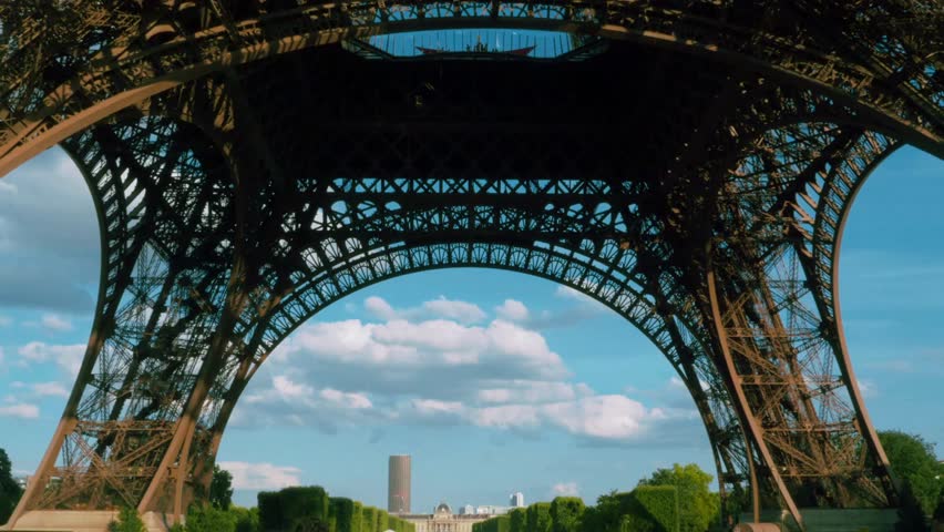 Looking up to the Eiffel Tower arch architecture. Under the Eiffel Tower, Paris. cinematic view from under the landmark. Tilt view to leg and top of Eiffel tower from under the Paris landmark.