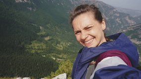 A cheerful young woman takes a selfie against the backdrop of mountains during her trip - Powered by Shutterstock - Get 15% off with code: PIKWIZARD15