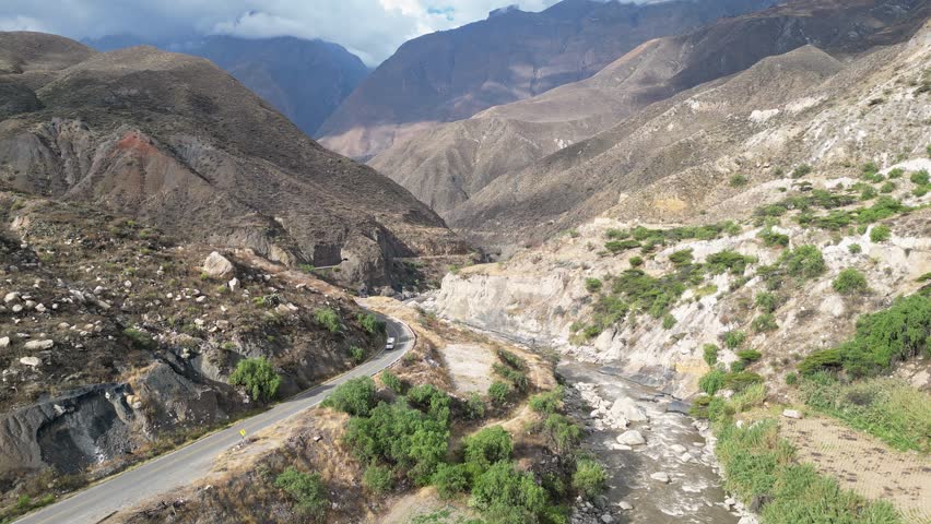 Huaraz, Peru: Aerial drone footage above narrow road in to canon del pato in Huaraz region, Peru. Taken with forward motion with dramatic mountains in the background and river flowing by the valley