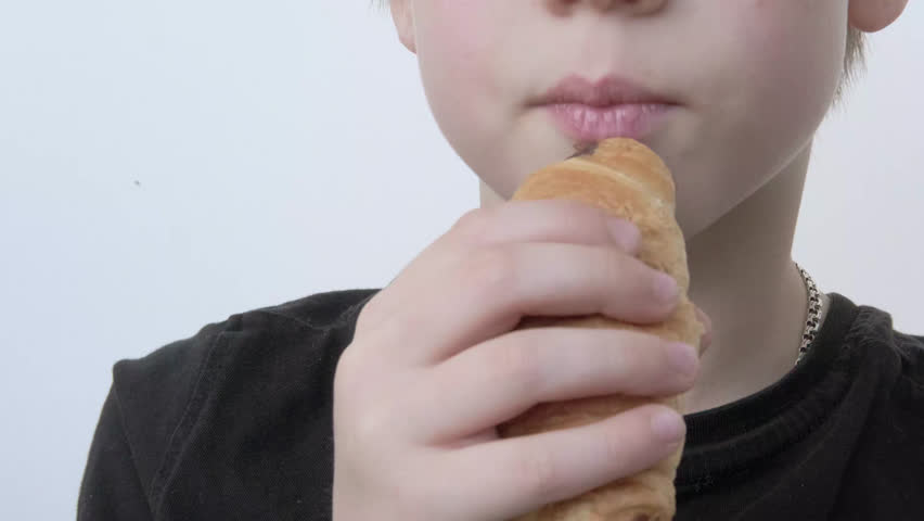 child, Young 10-year-old boy eating fresh croissant, chewing sweets pastry, kid has good appetite, happy childhood, balanced diet, sweet life, unhealthy food
