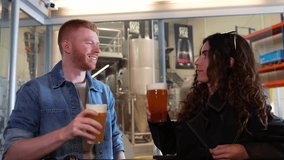 Cheerful young man and woman making a toast with pint glasses. Happy friends enjoying a fresh craft beer tasting inside a microbrewery - Powered by Shutterstock - Get 15% off with code: PIKWIZARD15