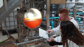 Male and female brewers monitoring the beer production process in a modern brewery. Colleagues discussing data from a clipboard near a vat - Powered by Shutterstock - Get 15% off with code: PIKWIZARD15