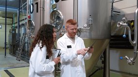 Male and female brewers in white coats discussing the beer production process. Technologists checking data on a clipboard in a modern craft brewery - Powered by Shutterstock - Get 15% off with code: PIKWIZARD15