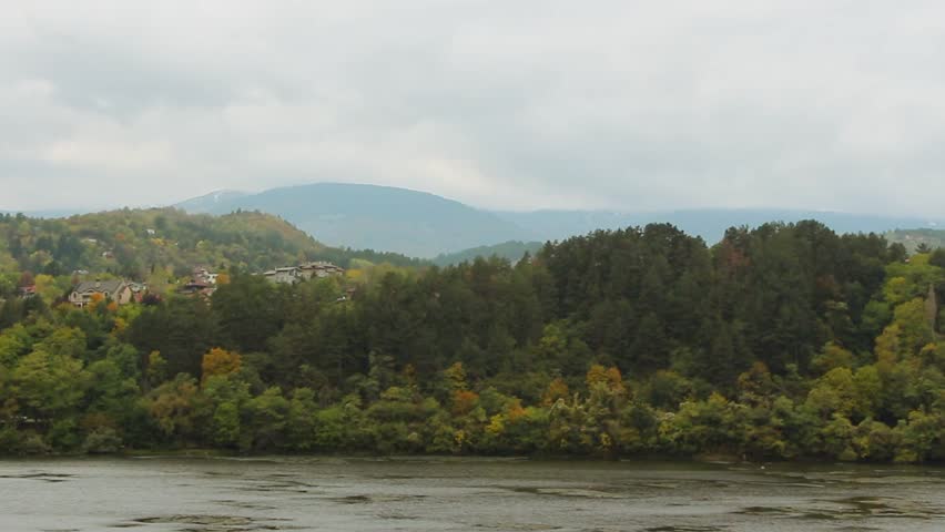 Scenic mountain village landscape with river and road on a moody, cloudy day