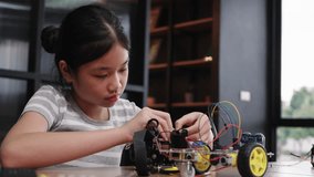 Asian girl concentrating while assembling a robot during robotics class, learning technology and problem solving with focus and curiosity, STEM education. - Powered by Shutterstock - Get 15% off with code: PIKWIZARD15