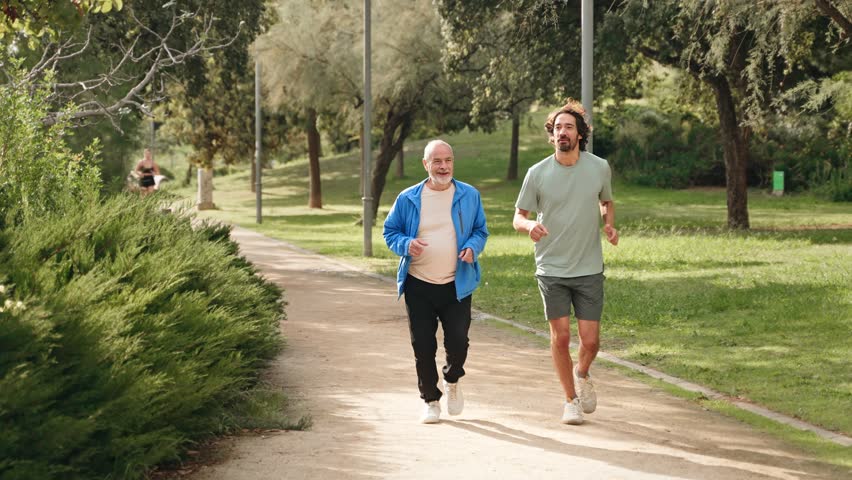 Senior dad man jogging doing sport together with his son, running for healthy lifestyle and family bonding